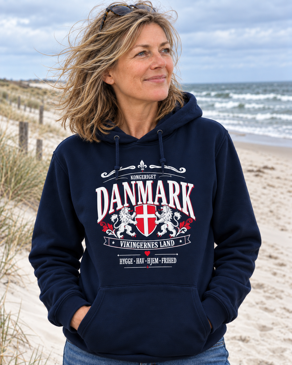 Frau am Strand mit dunkelblauem Hoodie und Danmark-Wappenmotiv mit Löwen und dänischer Flagge